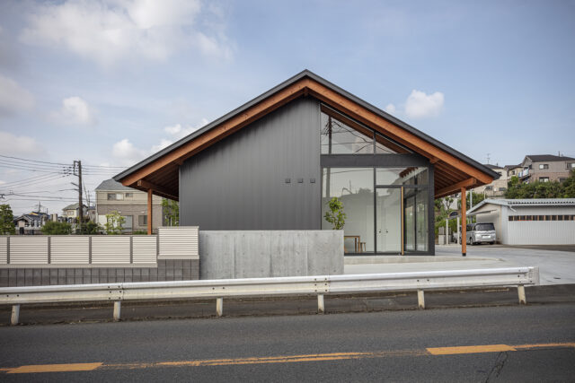 敷地の東を走る街道から見た「大屋根の家」。邸内には2階もあるが、切妻屋根をゆったりかけたシンプルなデザインで「平屋風の日本的な家」という要望に応えた。東面の約半分がガラス張りになった斬新さも魅力