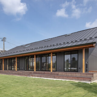 南の外観。柱は意匠としての化粧柱も入れて列柱をデザイン。高原のリゾートヴィラを彷彿とさせる高級感が生まれ、鮮やかな緑の庭とも好相性。連続する柱はウッドデッキののびやかな奥行きを強調する効果もある