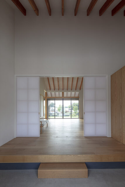 天井は高いがコンパクトな玄関ホール。障子戸を開けると垂木の先の庭まで一気に視線が抜け、開放感に感動