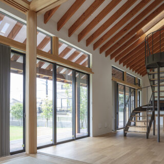 オブジェのような階段でリビング（手前）とダイニング（奥）をゾーニング。南は大きく開口し、要望の1つだった「日当たり、風通し」も実現。写真右に進むと勝手口に続く廊下や玄関があり、風が気持ちよく通る。天井には複数の天窓を設け、上からの採光や上下の風の流れも確保