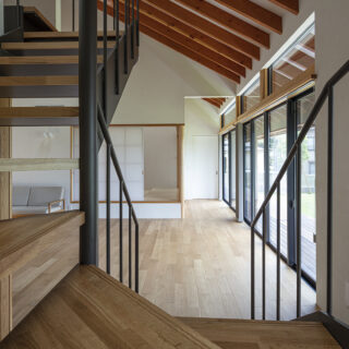 2階への階段からリビングや小上がりの和室を見る。曲線を描くオリジナリティあふれる階段は矢島さんのデザイン。意匠にこだわりつつ、高齢になってものぼりやすいよう段差の浅い階段を設計した。住まう人への思いやりを感じられる温かな配慮がうれしい