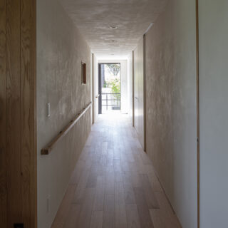 寝室への廊下。巾木をなくし、全面に珪藻土＋漆喰を左官塗りした壁のテクスチャーが趣深い陰影を生んでいる