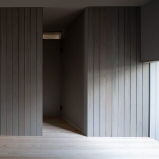 グレーの杉板張の主寝室は、落ち着きある雰囲気。大きな窓の先には坪庭があり、内と外がつながるかのよう。外からの視線は、垂れ壁と玄関前にある壁がしっかりと遮ってくれる。