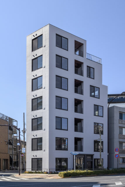 目白通り沿いのY字路のホームベース型の土地に建つFABRIC東長崎。周囲の街並みに溶け込むグレーを採用。同じサイズの窓が規則正しく連続し、バルコニーの突出もないため、スッキリした印象だ。