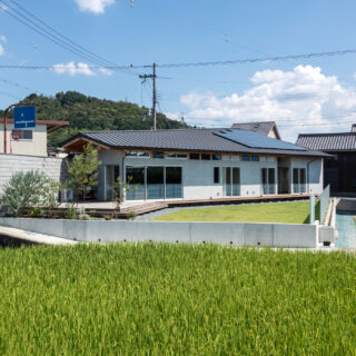道路側の境界壁は敷地いっぱいに建てられ、視線をカットする役割も持つ。一方で手前の水田側は高低差もあるため、境界壁は設けていない。眼前に広がる水田の光景を楽しむためのプランだ。広い庭やウッドデッキでは、BBQやテントを張って楽しんでいるそうだ