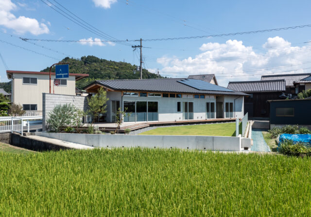 道路側の境界壁は敷地いっぱいに建てられ、視線をカットする役割も持つ。一方で手前の水田側は高低差もあるため、境界壁は設けていない。眼前に広がる水田の光景を楽しむためのプランだ。広い庭やウッドデッキでは、BBQやテントを張って楽しんでいるそうだ