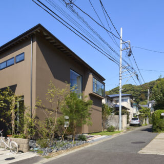 谷戸の坂道を上ると見えてくる石川邸。茶色いジョリパットで仕上げられた落ち着きある佇まい。様々な植栽が四季折々の表情をみせてくれる。