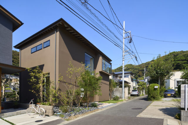 谷戸の坂道を上ると見えてくる石川邸。茶色いジョリパットで仕上げられた落ち着きある佇まい。様々な植栽が四季折々の表情をみせてくれる。