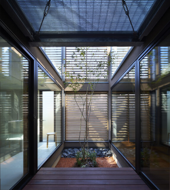 ビル用サッシを用いて実現した中庭の大開口。上部やルーバーからの光や風を導く。
中央に植えられたもみじも、季節感を与えてくれる存在。夏にはこのデッキでお子さんがプール遊びを楽しんだという。