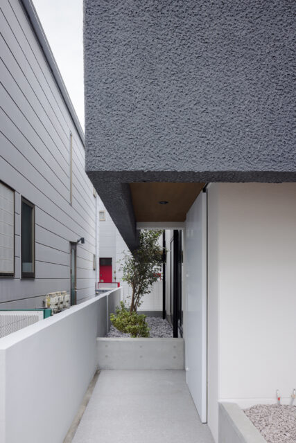 玄関へのエントランスは、通りからの視線を遮るよう、実家との境界に設けた。実家との行き来もしやすい配置。