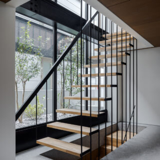 スケルトンの鉄骨階段は光を遮らないよう吊り構造で。オブジェのような美しさを放っている。窓の先には木々が植えられ、この家と共に成長し、やがて心地よい木陰を生み出すことだろう。
