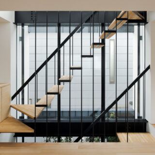 ３階まで続く大窓からの光が室内を明るく照らす。階段はこの光を邪魔しないよう細い丸鋼で吊る構造とした。