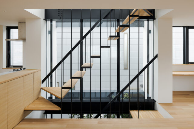 ３階まで続く大窓からの光が室内を明るく照らす。階段はこの光を邪魔しないよう細い丸鋼で吊る構造とした。