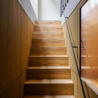 こちらの階段は上階とは趣を変え、木の温もりを感じさせる仕上げに。途中の壁は一部をアクリル製とし、上階からの光を地下まで導く工夫を施した