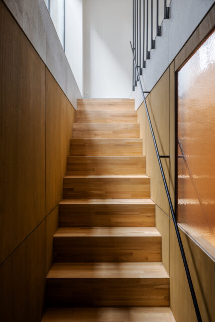 こちらの階段は上階とは趣を変え、木の温もりを感じさせる仕上げに。途中の壁は一部をアクリル製とし、上階からの光を地下まで導く工夫を施した