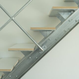 階段は、無骨なイメージを表現するため、また印象がシンプルになりすぎないよう、デザインの足し算を施した。ビスは強度的には必要ないが、鉄の質感をより強く押し出すためにつけた。踏板のシナ合板は表面を白く塗装し、側面の共芯の表情は楽しめるようにした