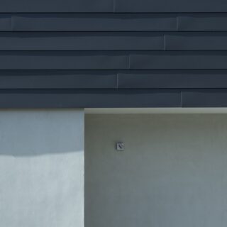 外壁。中央に見えるのは照明。2階のガルバリウム合板は、横幅を複数に分け、継ぎ目が重ならないよう張った