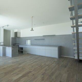 1階LDK。左奥のキッチンカウンターの一角を凹ませ、食事用のテーブル使用できるようにした。ダイニングテーブルとしてと、キッチンカウンターとしてでは適した高さが異なるため、キッチンの床レベルを下げて調節。両方の用途で快適に使えるようにした