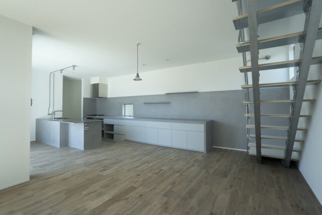 1階LDK。左奥のキッチンカウンターの一角を凹ませ、食事用のテーブル使用できるようにした。ダイニングテーブルとしてと、キッチンカウンターとしてでは適した高さが異なるため、キッチンの床レベルを下げて調節。両方の用途で快適に使えるようにした