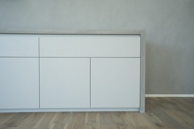 1階、キッチン背面からダイニングまで伸びる収納。プッシュラッチのおかげで、空間全体のシンプル、ミニマルな印象を損なわずに大容量の収納を設置できた。壁面に余計なものを出さないため、コンセントはカウンターの上部に設けた