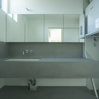 洗面脱衣室。洗面台の下は予定のラックやカゴが入る高さに計画。ご要望からアイロン台も置けるようしている。洗濯に関する家事はこの場所で全部完結できる