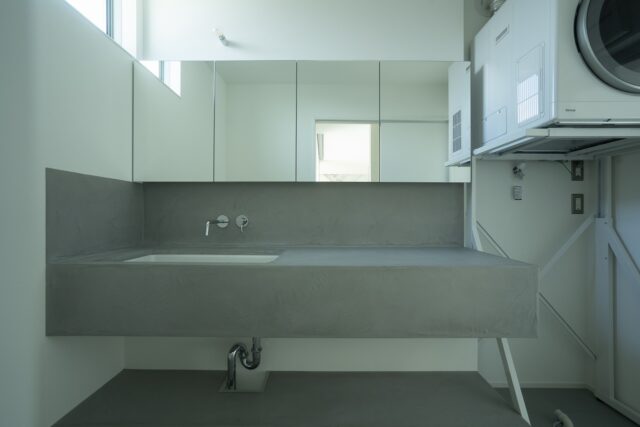 洗面脱衣室。洗面台の下は予定のラックやカゴが入る高さに計画。ご要望からアイロン台も置けるようしている。洗濯に関する家事はこの場所で全部完結できる