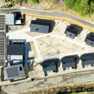 全景。切妻屋根が宿泊施設の建物。左端が共用棟。そこから時計回りに、C棟（1棟）、B（2棟）、A棟（3棟）。A棟の下に川が流れており、ホテルへは左下の橋を渡ってアプローチする。そのため、ホテル内は日常から一つ離れた世界という感覚が得られるよう計画した
