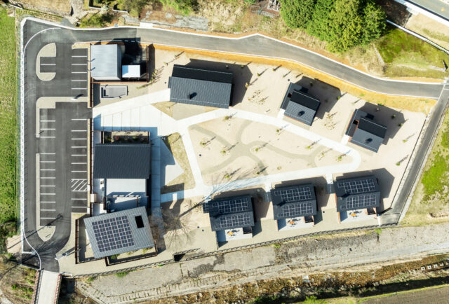 全景。切妻屋根が宿泊施設の建物。左端が共用棟。そこから時計回りに、C棟（1棟）、B（2棟）、A棟（3棟）。A棟の下に川が流れており、ホテルへは左下の橋を渡ってアプローチする。そのため、ホテル内は日常から一つ離れた世界という感覚が得られるよう計画した