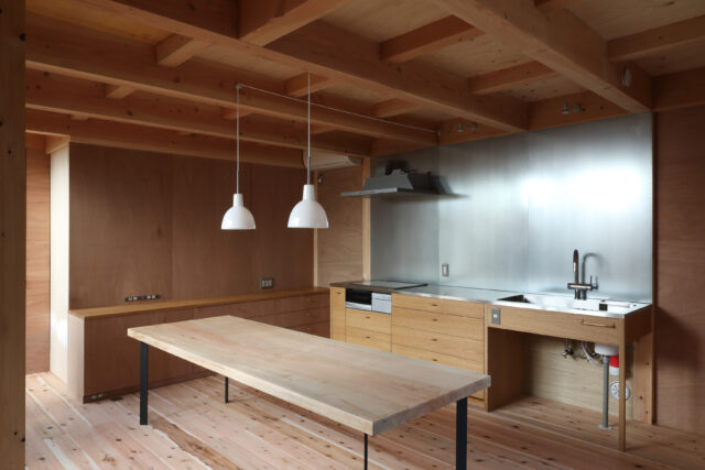 キッチン・ダイニング。家具やテーブルはすべて造作だ。キッチンの壁面は金属素材のZAM。高耐食性メッキ鋼板で磁石が使え、錆びにくい。デザイン面でのアクセントと掃除などのしやすさも採用の理由となった。鴨居に照明を組み込み、このスペースもシンプルに