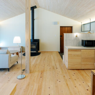 A棟。キングベッドの辺りから玄関方向を見渡す。ラグジュアリーなA棟は、ヒノキの床に加えて天井にもヒノキを張った。壁は漆喰の塗壁とし、木や自然素材の温もりが存分に感じられる空間をつくり上げた。薪ストーブで暖を取る、そのちょっとしたひと手間が贅沢な時間を演出する
