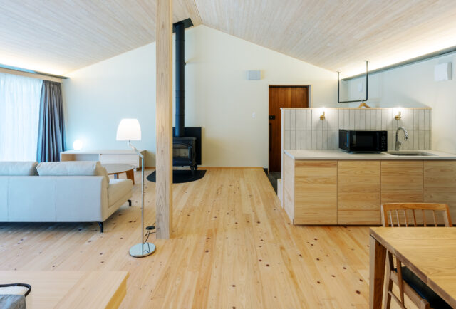 A棟。キングベッドの辺りから玄関方向を見渡す。ラグジュアリーなA棟は、ヒノキの床に加えて天井にもヒノキを張った。壁は漆喰の塗壁とし、木や自然素材の温もりが存分に感じられる空間をつくり上げた。薪ストーブで暖を取る、そのちょっとしたひと手間が贅沢な時間を演出する