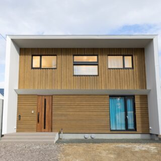 外観。家を囲む深い軒と、1階と2階の間の浅目の軒は南からの日射をコントロールする役目も担う。1階と2階で外壁の板目に変化を持たせ、シンプルながら目を引くデザインを実現。屋根の両側に設けた小さな庇は奥にあるおかげで正面から見えづらく、デザインに干渉しない