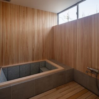 １階、浴室。「日常とは異なる体験をして癒されて帰って欲しい」というオーナー様の要望を実現した檜風呂。昼間に使用するため、ハイサイドライトから日射を取り入れ、より贅沢な時間を過ごしてもらえるよう環境を整えた