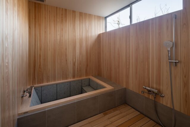 １階、浴室。「日常とは異なる体験をして癒されて帰って欲しい」というオーナー様の要望を実現した檜風呂。昼間に使用するため、ハイサイドライトから日射を取り入れ、より贅沢な時間を過ごしてもらえるよう環境を整えた