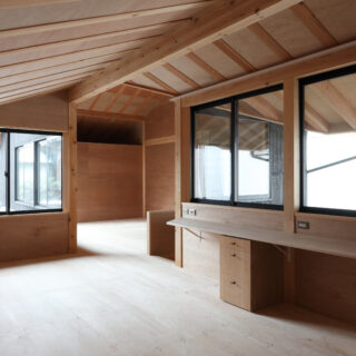 天井が低い側の2階。軒まで続く梁などの構造が見えて美しい。子供の勉強机が造作で準備されている。2階もすべて間接照明で、シンプルに仕上げられている