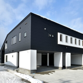 白と黒のモノトーンの外壁とシャープなラインが存在感を放つ外観。四角いボリュームと片流れ屋根のボリュームがくっつくL時の構造。