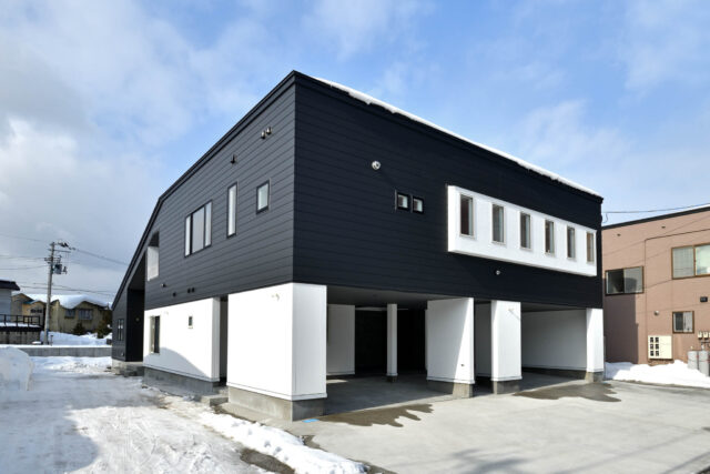 白と黒のモノトーンの外壁とシャープなラインが存在感を放つ外観。四角いボリュームと片流れ屋根のボリュームがくっつくL時の構造。
