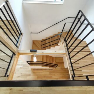 2階吹き抜けから1階を見下ろす。階段と2階を結ぶブリッジは要望から簀の子を採用。視線や光が抜け、縦のつながりが一層感じられるようになった。吹き抜けの上部には開閉できる窓を計画。風が通り、一年を通して快適に暮らせる