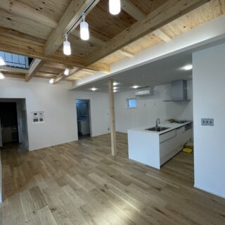 1階LDK。2階部分があるリビングエリアは構造材を表しにした天井を取り入れ、天井を高くとの要望を叶えた。キッチンはペニンシュラ型を採用、キッチントップをフラットにすることでLDK全体の見通しがよくなった。円滑なコミュニケーションに役立つ