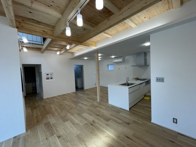 1階LDK。2階部分があるリビングエリアは構造材を表しにした天井を取り入れ、天井を高くとの要望を叶えた。キッチンはペニンシュラ型を採用、キッチントップをフラットにすることでLDK全体の見通しがよくなった。円滑なコミュニケーションに役立つ