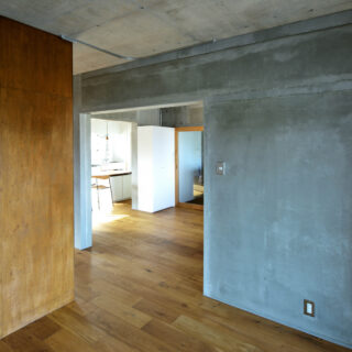 構造上、取り払うことのできないコンクリートの壁を現しに。無機質なだけの空間にならないよう、新たに造作したウォークインクローゼットはラワン合板で仕上げ、木の温もりをプラスした。いずれもラフな質感の素材のため相性がよく、見た目にも馴染んでいる