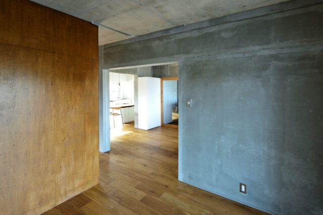 構造上、取り払うことのできないコンクリートの壁を現しに。無機質なだけの空間にならないよう、新たに造作したウォークインクローゼットはラワン合板で仕上げ、木の温もりをプラスした。いずれもラフな質感の素材のため相性がよく、見た目にも馴染んでいる