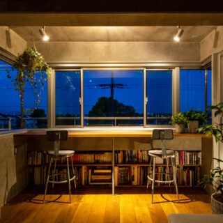 眺めのいい窓辺でクリエイティブな仕事ができたらと、リビングの一角に設えたカウンタースペース。カウンターテーブルの下に本棚を造作して使い勝手を高めた。三面採光で昼は明るく開放的、夜はスポットライトの灯りの下リラックスして過ごせる