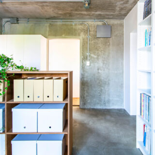 ワークスペースは玄関とひと続きの土間仕上げ。造作のシェルフを玄関との仕切りにも活用している