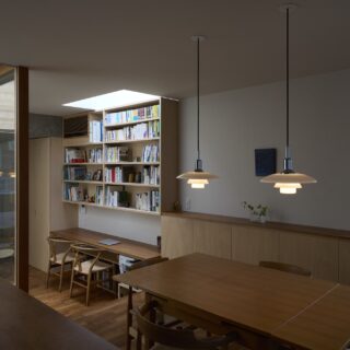 子世帯の通路（写真左）とダイニング（写真右）。天窓から光が入る中庭沿いの通路には、本棚やパソコン作業などができるカウンターを造り付け、スペースを有効活用。こうした造作家具や通路はミリ単位で計算し、ストレスなく動けてすっきり片付く快適空間を実現している