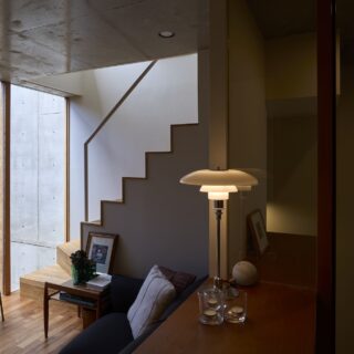 子世帯のリビングスペース（写真左）。コンパクトだが中庭に面しているので視線が通り、外光や上下の広がりを感じられる。中庭側は天井から床までガラスがはめ込まれて屋外との境界があいまいになり、室内なのにテラスにいるような居心地を味わえる