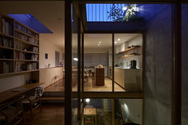 2階子世帯の夕景。ガラスの吹抜けの中庭を介して各フロアの空間が見え、ドールハウスのよう。中庭の分だけ床面積は減っているが、見通しが良くなってタテヨコの広がりが強調され、視覚的、体感的な開放感が格段に増している