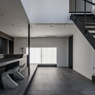 1階LDK。正方形のうち4分の1を吹き抜けとし、開放感をプラス。キッチン・ダイニングのエリアよりリビングのエリアの床レベルを下げ、段差を活用して居場所の多い空間をつくりあげた