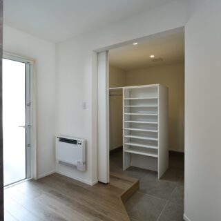 子世帯の玄関には、大容量のシューズクロークが。将来、ベビーカーなどを置くのにも重宝する空間。外へ出ず直接親世帯のキッチンと繋がる扉もあり、両世帯の程よい距離感の構築に一役買っている。