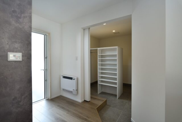 子世帯の玄関には、大容量のシューズクロークが。将来、ベビーカーなどを置くのにも重宝する空間。外へ出ず直接親世帯のキッチンと繋がる扉もあり、両世帯の程よい距離感の構築に一役買っている。